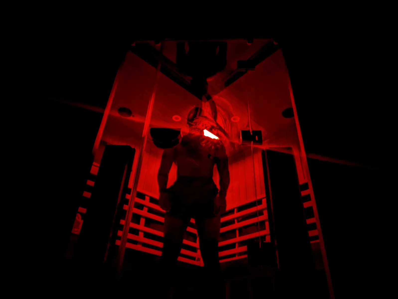 A figure silhouetted inside a red-lit infrared sauna